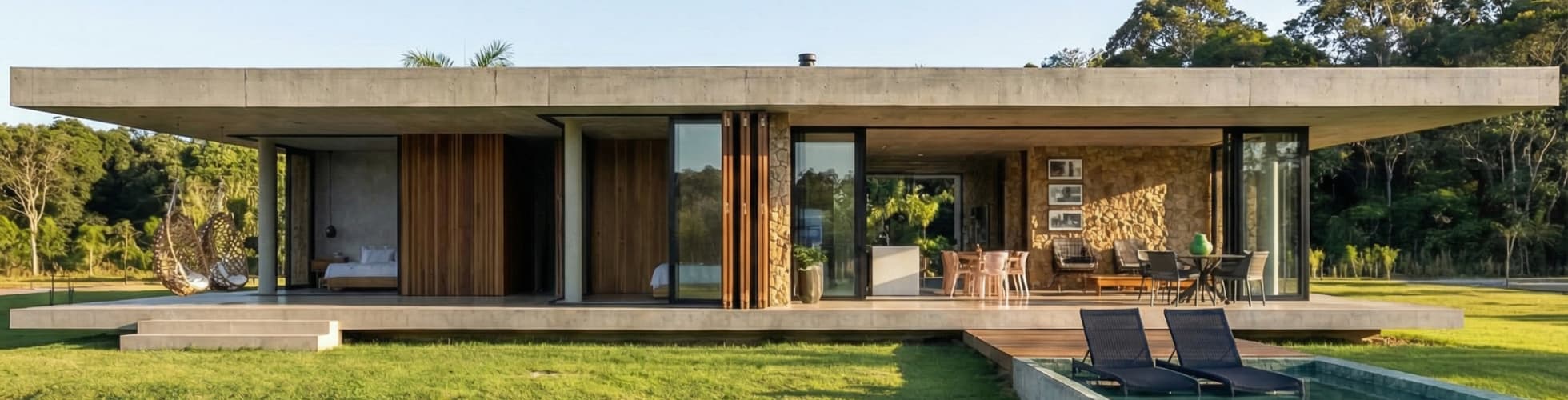 Fachada de luxo térrea com volumetria horizontal em concreto aparente e painéis ripados de madeira, parede rústica em pedra natural na área social, brises móveis de madeira e paisagismo integrado, projetada por arquiteto de alto padrão.