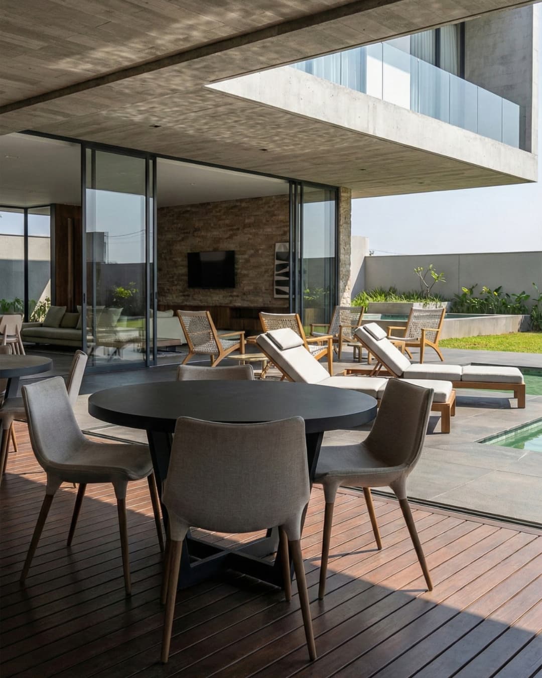 Varanda gourmet de luxo com deck de madeira, mobiliário contemporâneo, teto em concreto aparente e integração com sala de estar.
