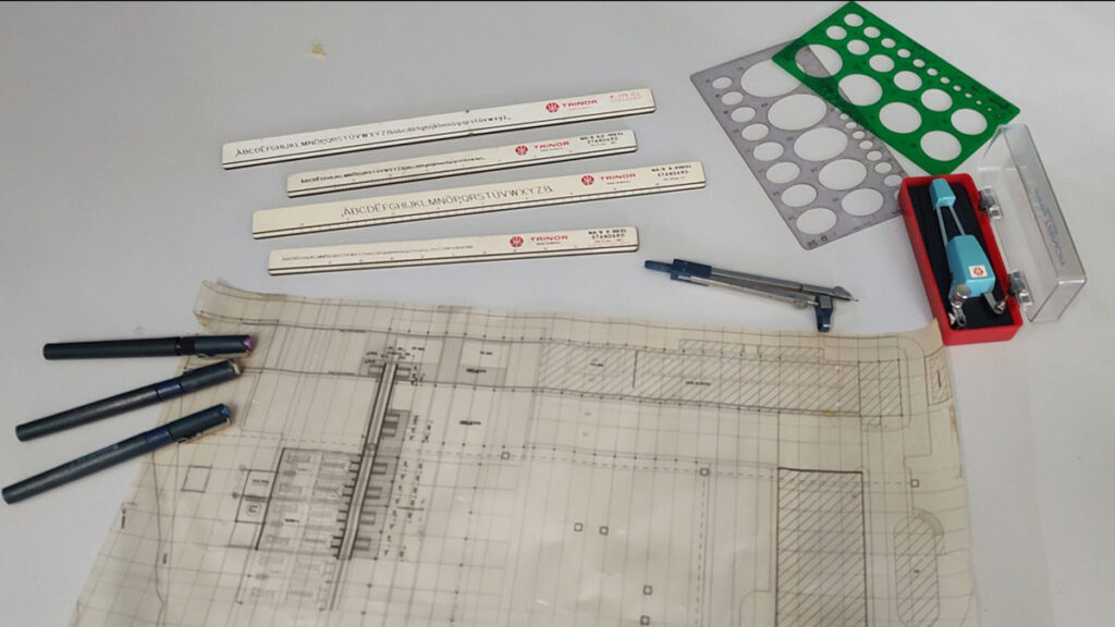 Instrumentos de desenho técnico: canetas nanquim de diferentes espessuras, régua paralela e esquadros sobre prancheta.