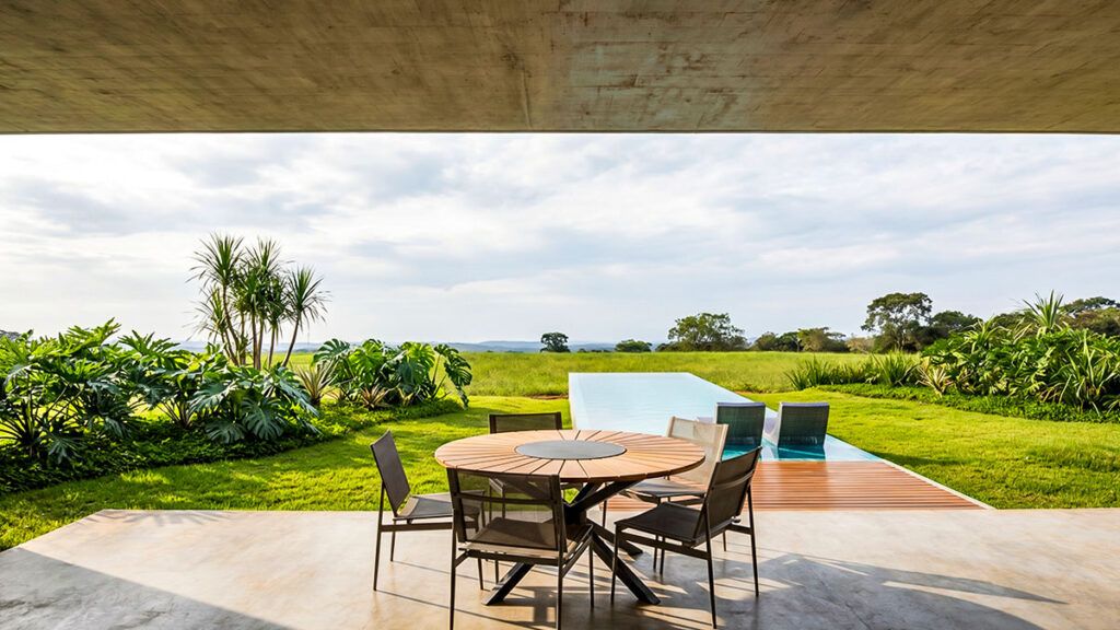 Sala de estar integrada à área externa com piscina, jardim e piscina em residência de alto padrão, projeto de Raphael Davila.
