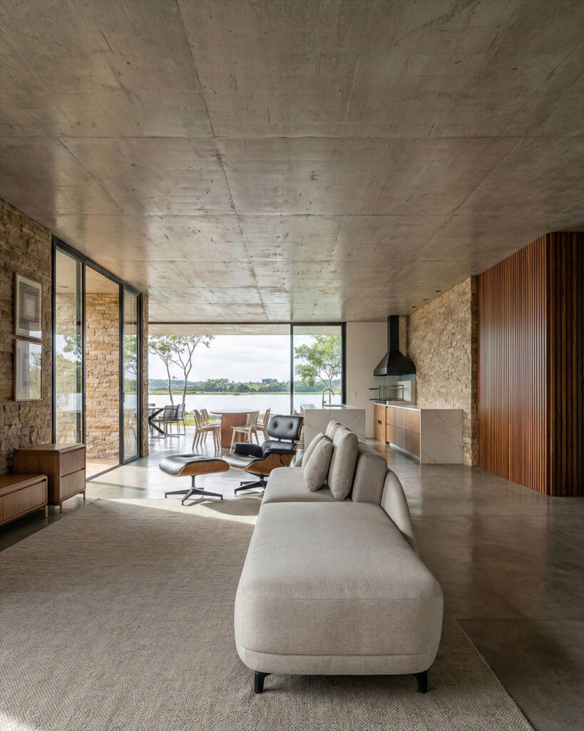 Interior de residência de alto padrão banhado por luz natural, com materiais naturais e integração com o exterior, projeto de Raphael Davila.