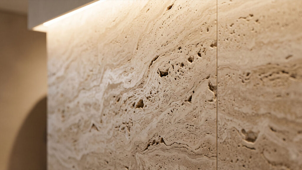 Detalhe de parede revestida em travertino romano com veios naturais e iluminação embutida de destaque superior.