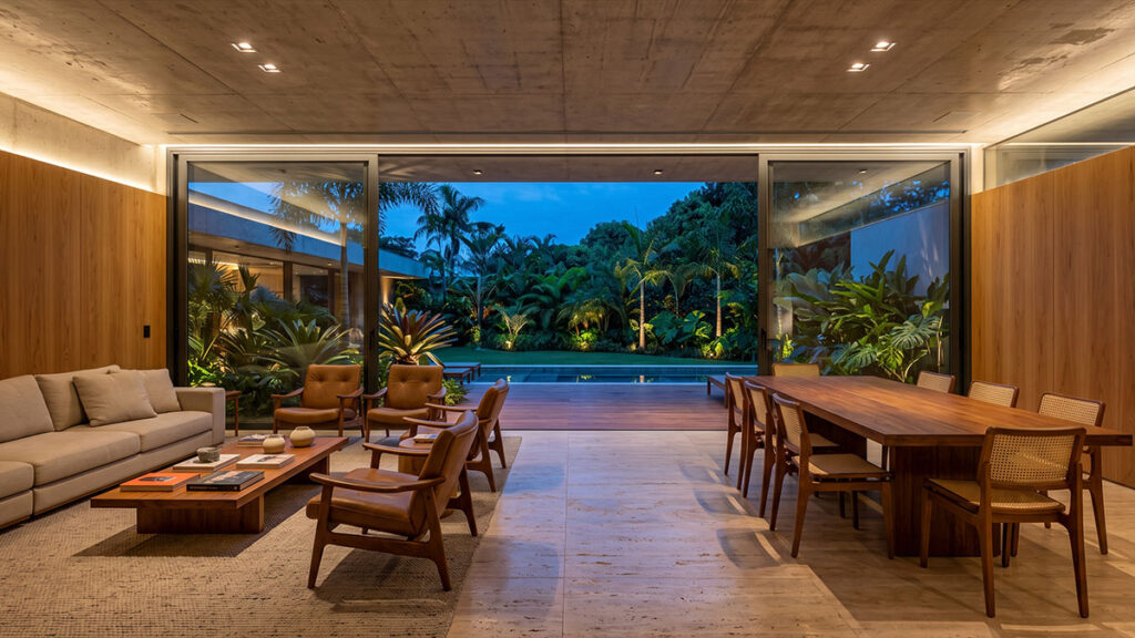 Estar e jantar integrados com grandes portas de vidro para jardim e piscina, teto em concreto aparente e painéis de madeira